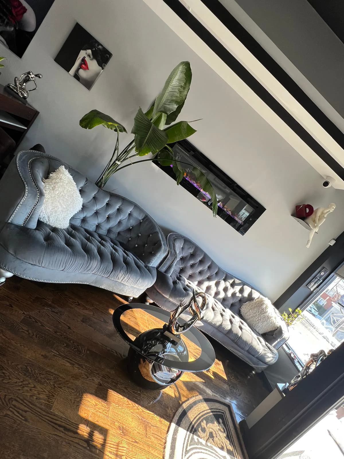 Waiting lounge with a tufted sofa and plants at Attraction Nails Salon